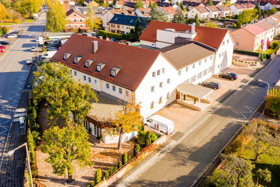 Aerial view of the highway hotel in Nuremberg and the surrounding houses, as well as some trees, bushes and cars